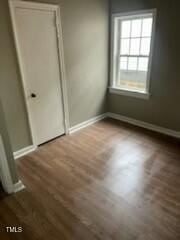 unfurnished bedroom with dark wood-style flooring and baseboards