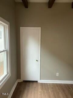 unfurnished bedroom featuring baseboards, beamed ceiling, and wood finished floors