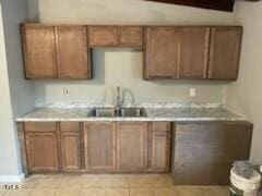 kitchen featuring light countertops, brown cabinetry, and a sink