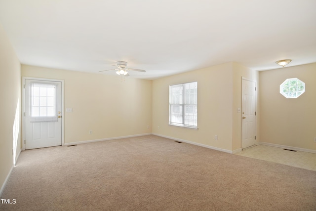 spare room with light carpet, ceiling fan, and baseboards