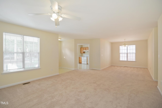 spare room with light carpet, baseboards, visible vents, and ceiling fan with notable chandelier