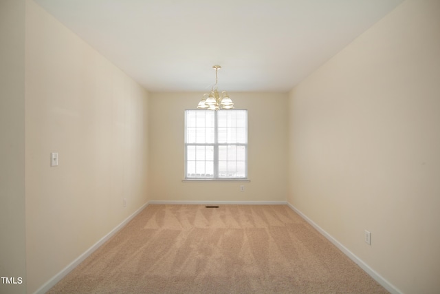 empty room with a chandelier, light carpet, visible vents, and baseboards