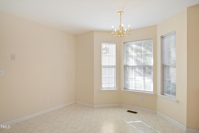 spare room featuring baseboards, visible vents, and a notable chandelier