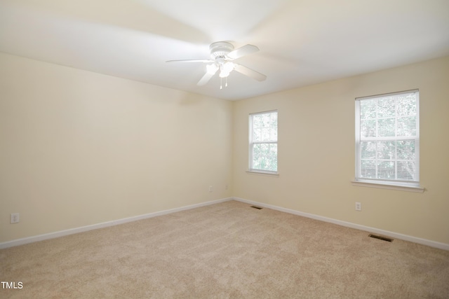 empty room featuring light colored carpet, visible vents, and baseboards