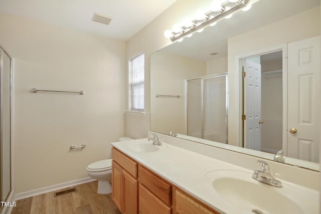 bathroom with toilet, a sink, visible vents, and a shower stall