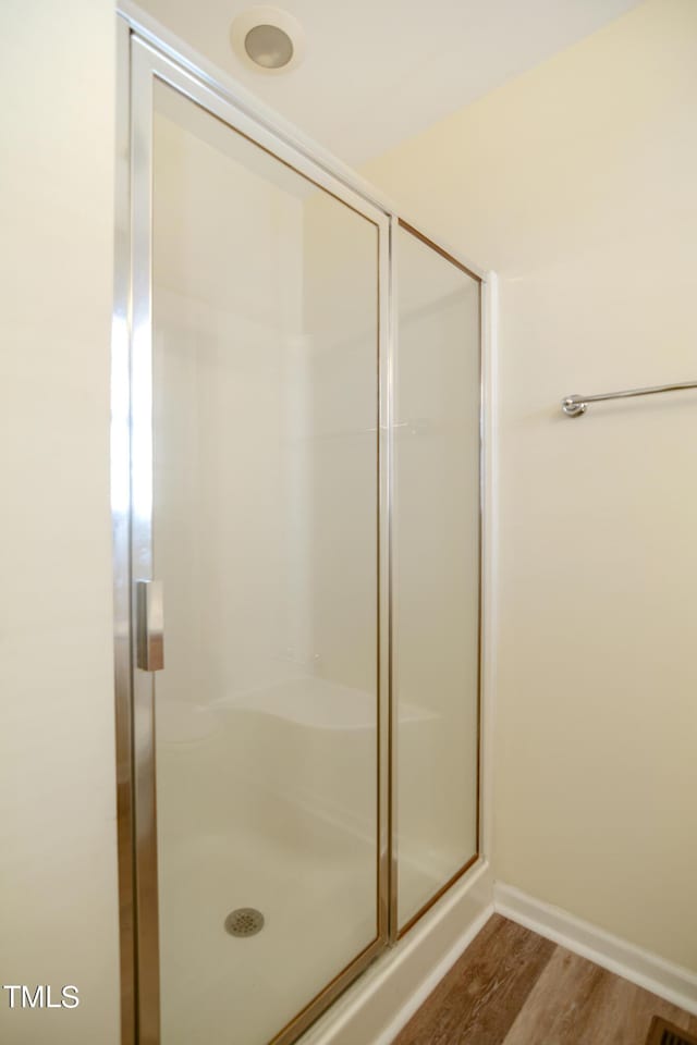 bathroom with a shower with door and wood finished floors