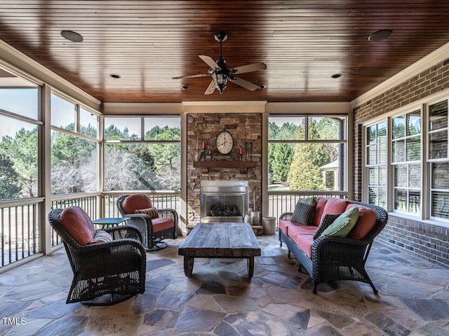 sunroom / solarium with a ceiling fan, wood ceiling, and a stone fireplace