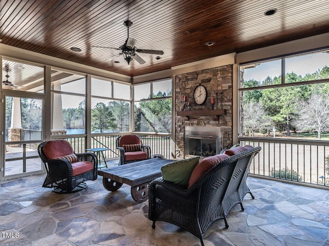 sunroom / solarium with a ceiling fan, wood ceiling, and a fireplace