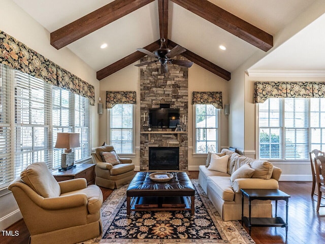 living area with beam ceiling, ceiling fan, a stone fireplace, and wood finished floors