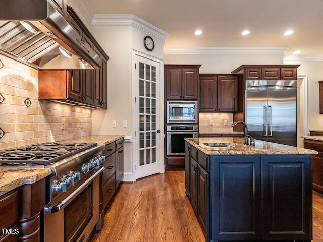 kitchen featuring built in appliances, dark wood-style flooring, a sink, ornamental molding, and range hood