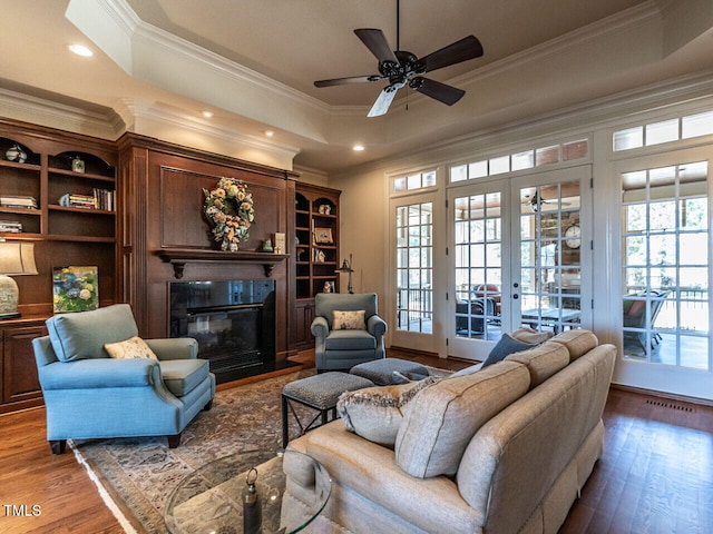 living area featuring wood finished floors, a tray ceiling, a fireplace with flush hearth, and a wealth of natural light