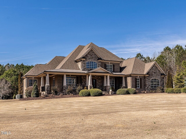 view of front of house featuring stone siding, a front lawn, and a porch