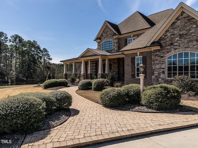 view of front of house with metal roof, stone siding, a porch, and a standing seam roof