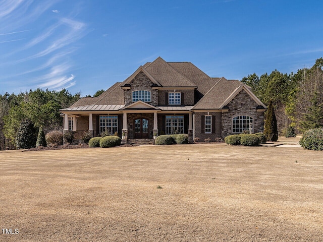 view of front of house with a standing seam roof, stone siding, a front lawn, and metal roof