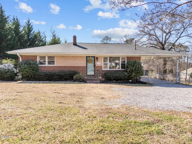 single story home with brick siding, fence, a front yard, a carport, and gravel driveway