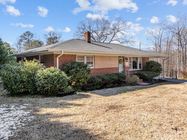 ranch-style home featuring roof with shingles, a chimney, a front lawn, and brick siding