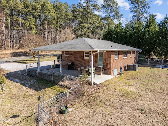 rear view of house featuring brick siding, central air condition unit, a lawn, entry steps, and fence