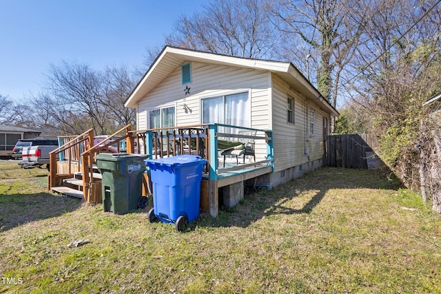 view of side of property with crawl space, a yard, a deck, and fence