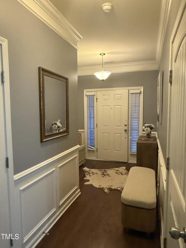 entrance foyer with visible vents, a decorative wall, crown molding, and wainscoting