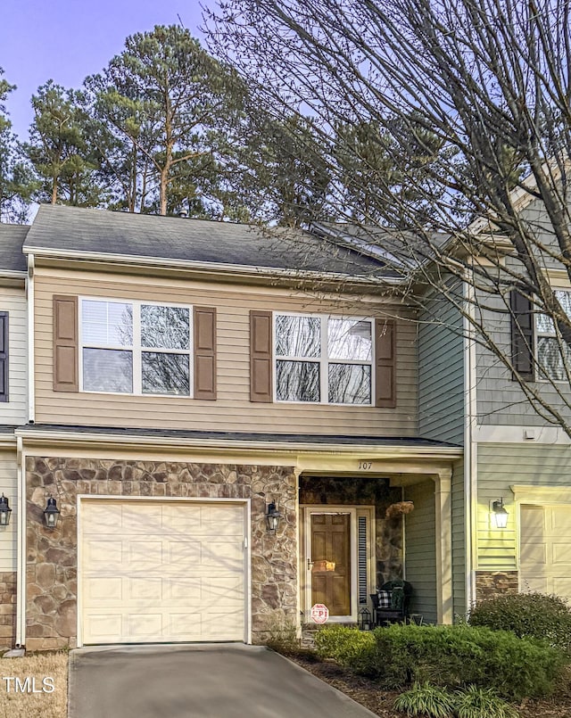 view of property with a garage, stone siding, and driveway