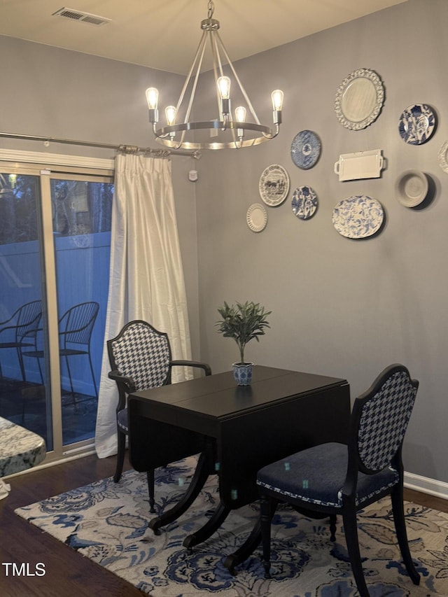 dining room with baseboards, a notable chandelier, visible vents, and wood finished floors