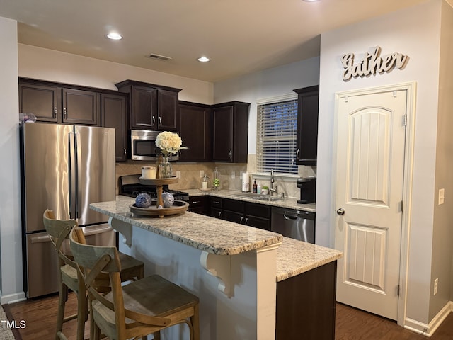 kitchen featuring stainless steel appliances, a sink, visible vents, a center island, and tasteful backsplash