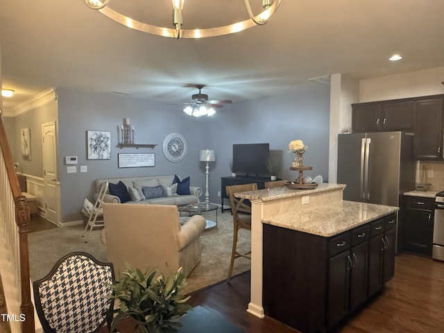 kitchen with ceiling fan, a kitchen island, a breakfast bar area, open floor plan, and freestanding refrigerator