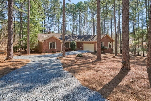 view of front of property with driveway, a garage, a chimney, crawl space, and brick siding