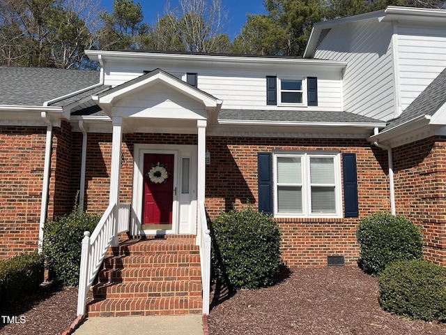 view of front of property with roof with shingles, brick siding, and crawl space