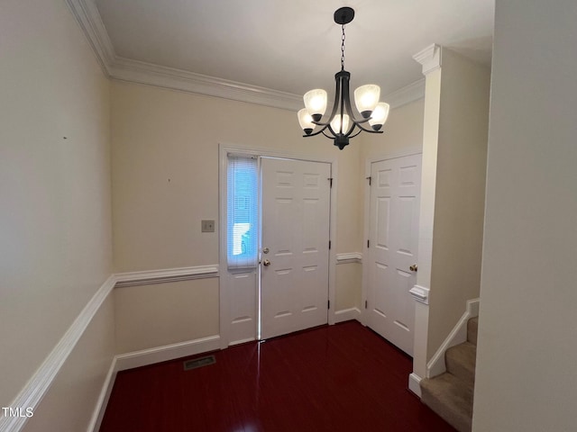 foyer with baseboards, visible vents, dark wood finished floors, crown molding, and a chandelier