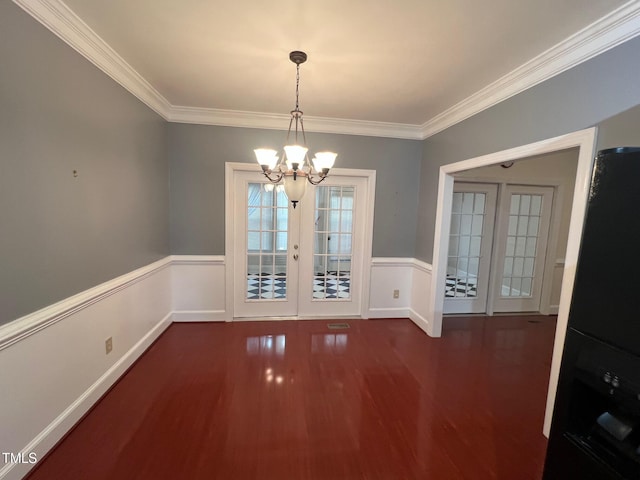 unfurnished dining area with a wainscoted wall, ornamental molding, wood finished floors, and french doors