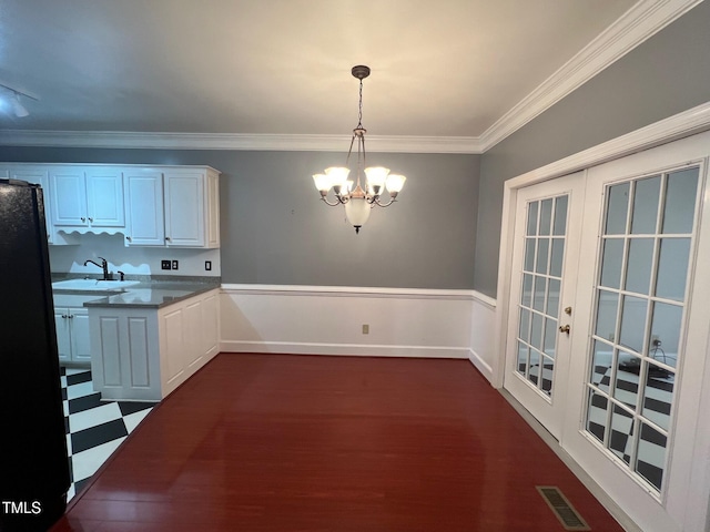 kitchen with visible vents, ornamental molding, freestanding refrigerator, an inviting chandelier, and a sink