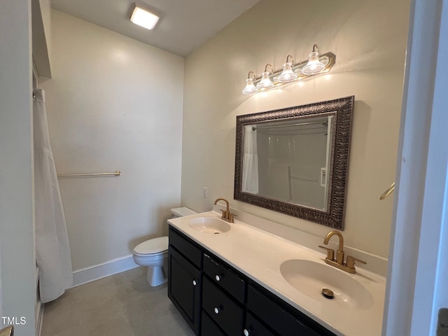 bathroom with double vanity, a sink, toilet, and baseboards