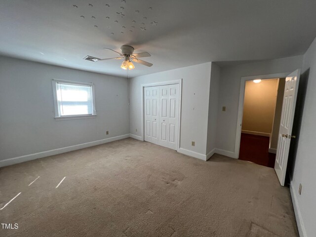 unfurnished bedroom with visible vents, baseboards, a ceiling fan, carpet, and a closet