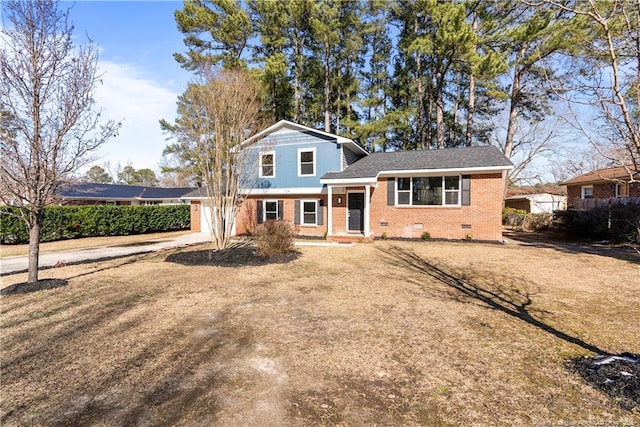 split level home featuring brick siding, concrete driveway, an attached garage, crawl space, and a front lawn