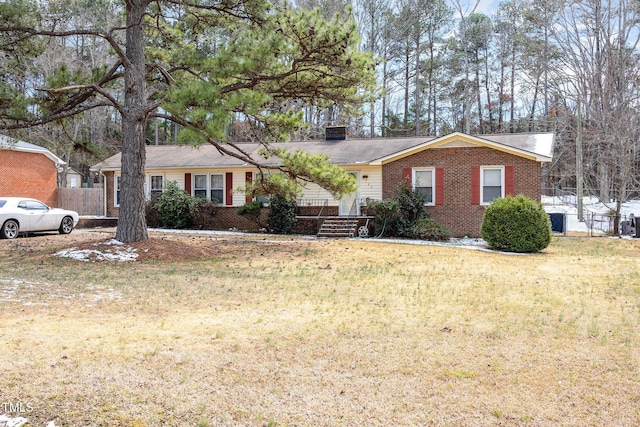 ranch-style house featuring a front yard, a chimney, and brick siding