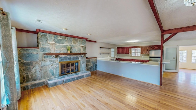 unfurnished living room featuring light wood-type flooring, plenty of natural light, a fireplace, and visible vents