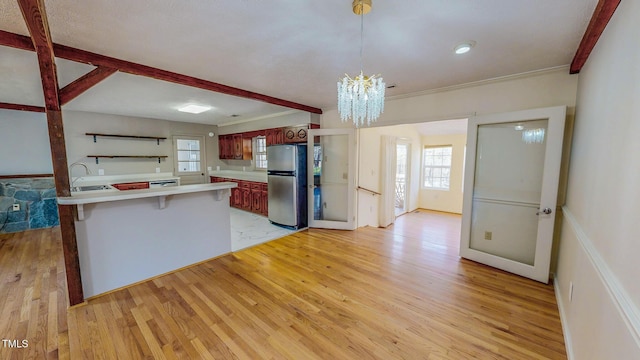 kitchen featuring a peninsula, light wood finished floors, light countertops, and freestanding refrigerator