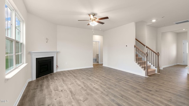 unfurnished living room featuring baseboards, visible vents, stairway, wood finished floors, and a fireplace