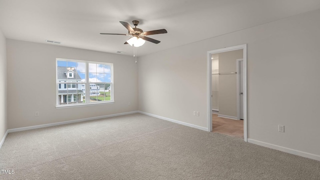 empty room with light carpet, ceiling fan, visible vents, and baseboards