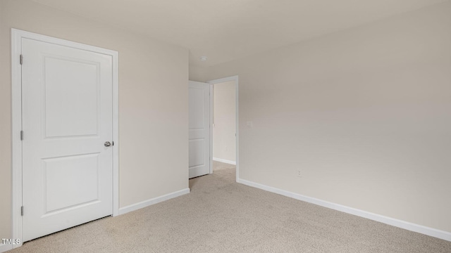 unfurnished bedroom featuring light carpet and baseboards