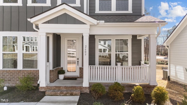 property entrance with board and batten siding, brick siding, and a shingled roof