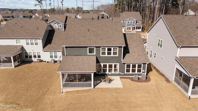 back of house with roof with shingles, a patio area, a residential view, and a sunroom