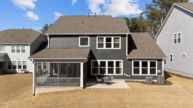 back of property featuring a shingled roof, a lawn, a patio area, and a sunroom