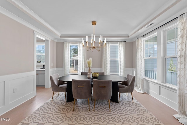 dining room featuring visible vents, a decorative wall, wainscoting, a chandelier, and light wood-type flooring