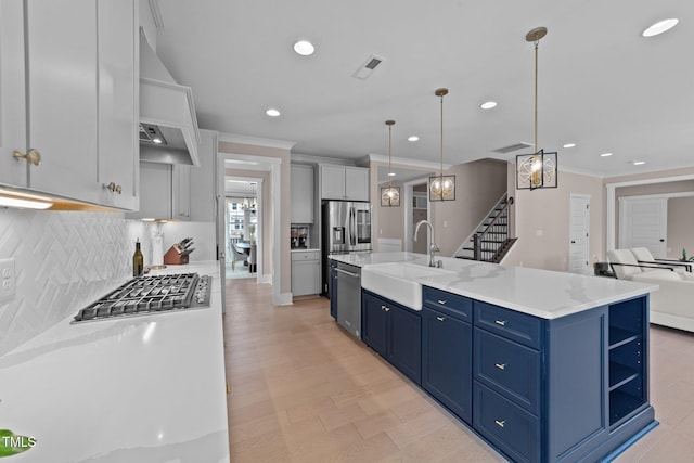 kitchen with pendant lighting, a center island with sink, appliances with stainless steel finishes, open floor plan, and a sink