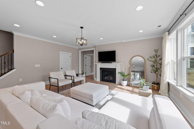 living room with light wood finished floors, a glass covered fireplace, ornamental molding, stairs, and recessed lighting