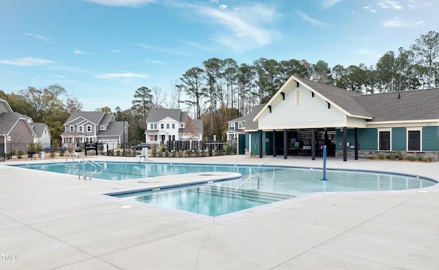 community pool with a patio area and fence