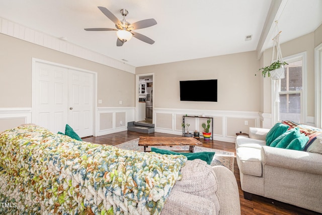 living area with ceiling fan, wainscoting, dark wood finished floors, and visible vents