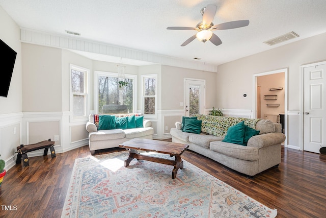 living room with dark wood-style floors, wainscoting, visible vents, and a textured ceiling